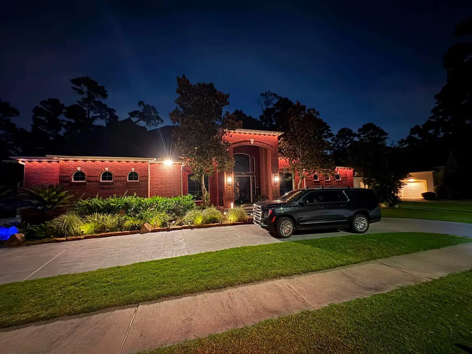 A real Skyclear permanent-lighting install glowing on a Houston brick home at night