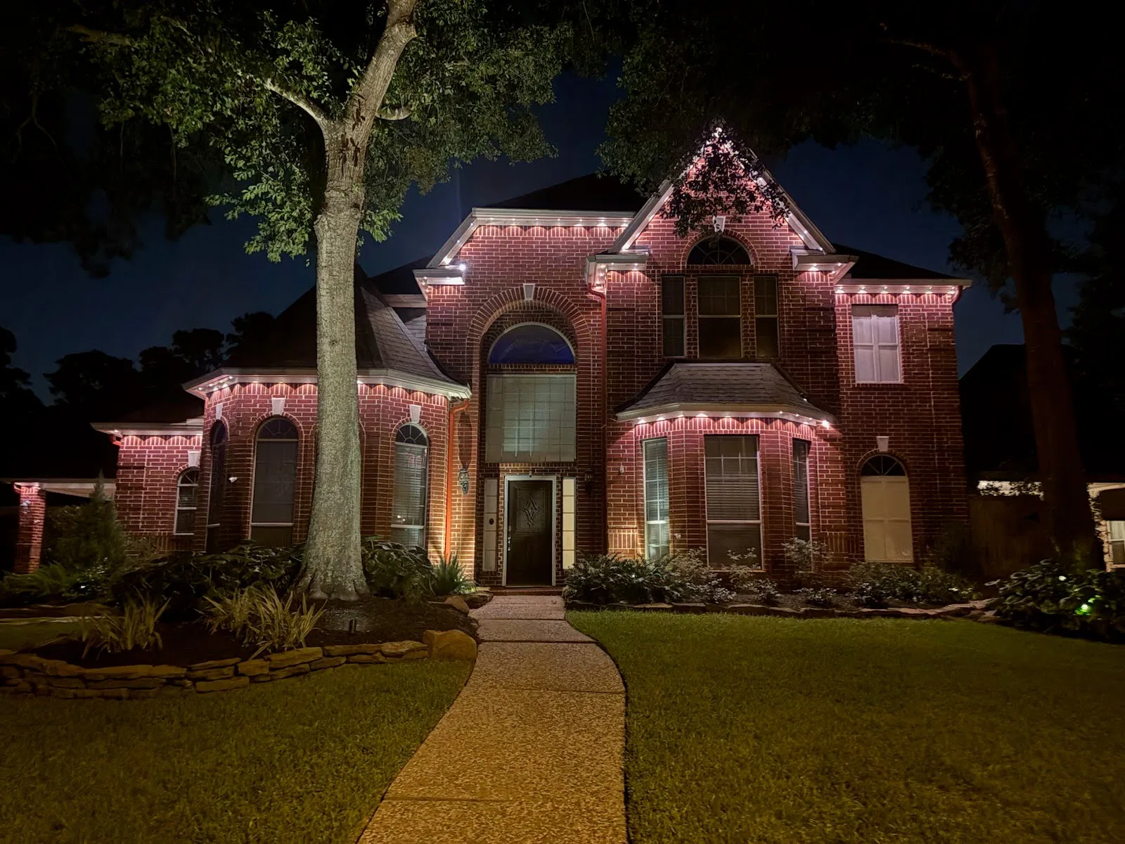 A real Skyclear two-story warm-white permanent roofline lighting installation on a brick home