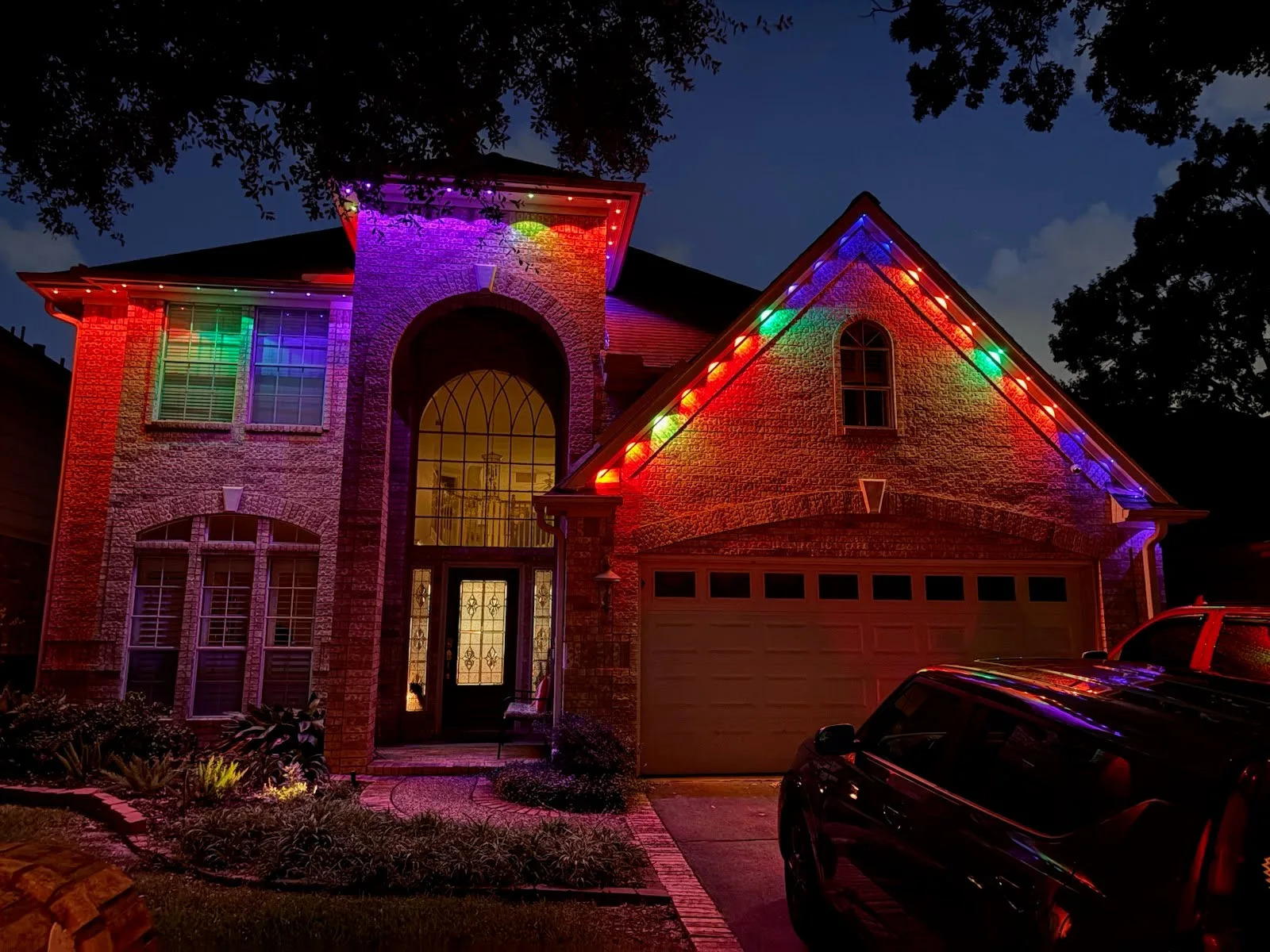 Real Skyclear install — Houston brick home with permanent roofline lighting in full multicolor at night